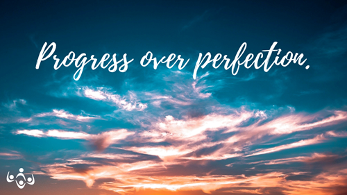 The words "Progress over perfection" in a script over a pink and teal cloudy sky.
