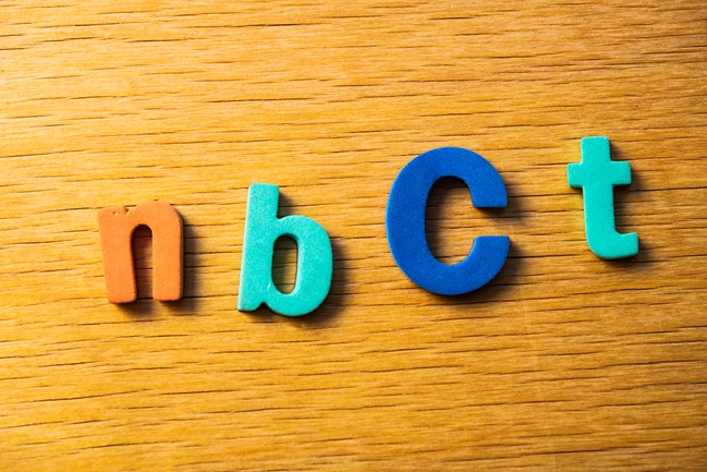 Foam letters spell out "NBCT" on a desktop.